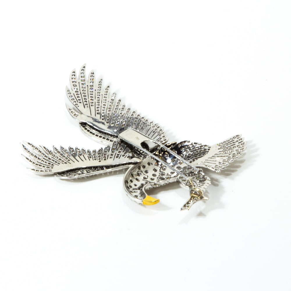 Diamond & White Gold Eagle Clip: Diamond and white gold eagle brooch, modeled as a hunting eagle in flight clutching its' prey, set with approximately 450 round brilliant-cut diamonds, total approximately 4.50 cts., one ruby eye and 