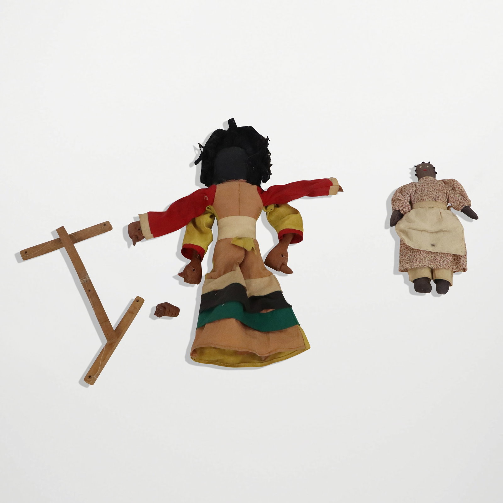 Black Americana Folk Art Rag Dolls, 2: Two Black Americana Folk Art rag dolls, early 20th century, comprising a smaller hand-stitched doll with embroidered details at face, and a marionette mounted rag doll with terra cotta details at hand