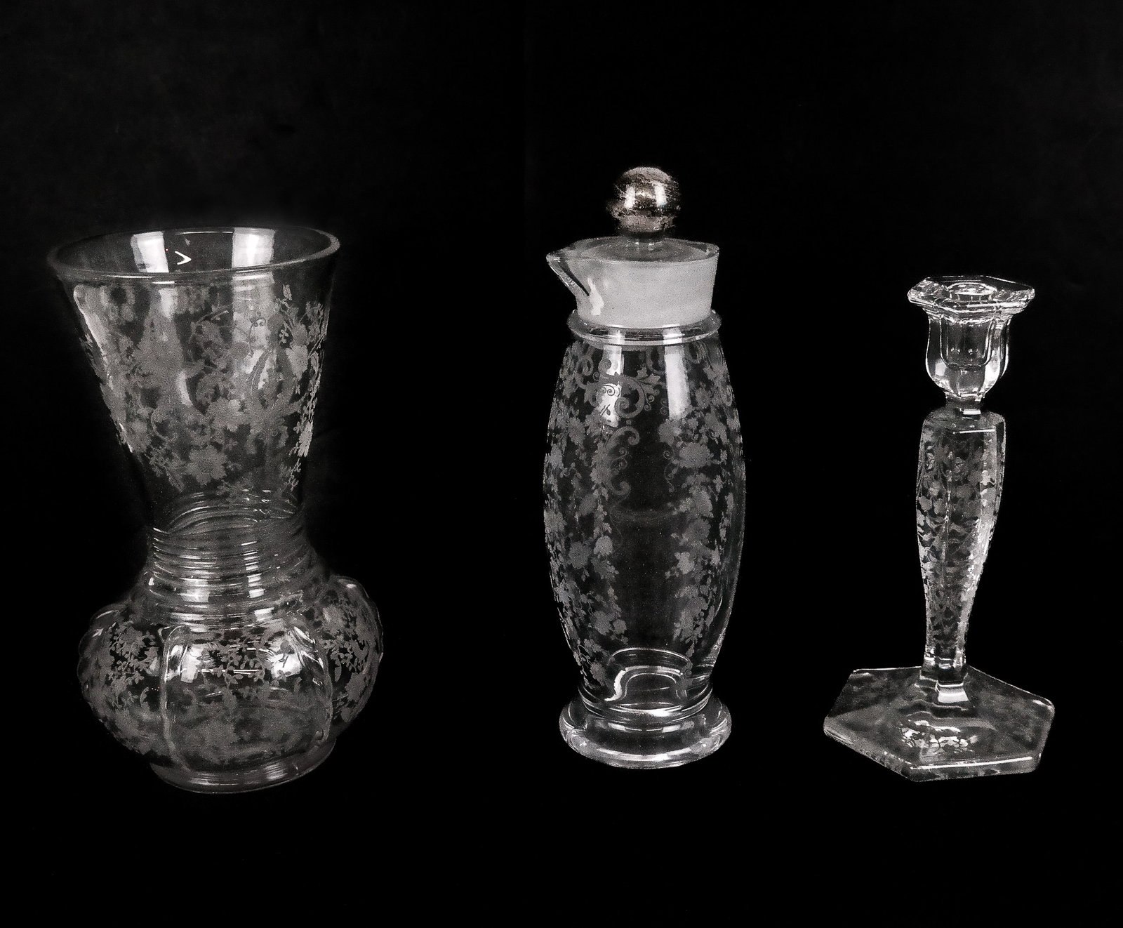 Three Vintage Etched Glass Vessels: Group of floral etched glass items, comprising a candlestick [9.25" H x 5" Diameter], a molded and etched glass vase [10.25" H x 5" Diameter], and a decanter with double pour spouts with a sterling si