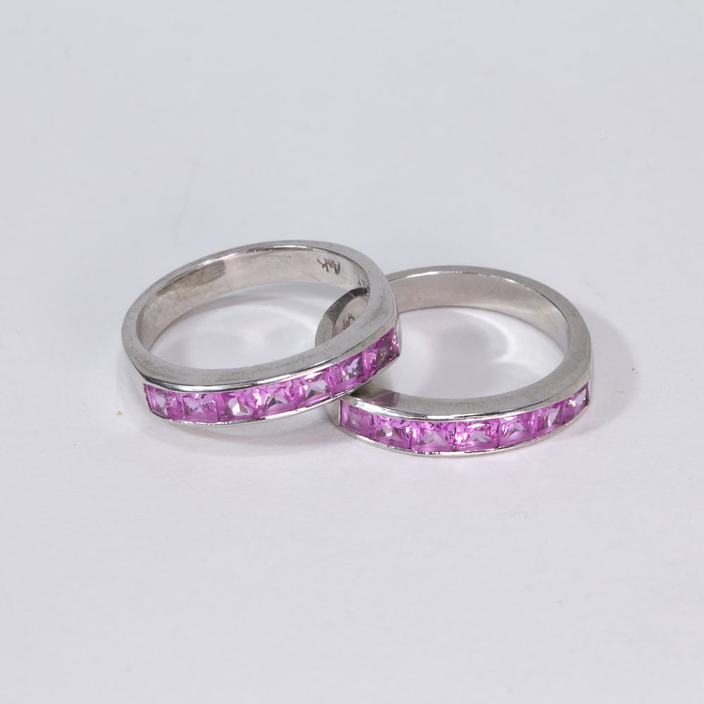 Pair of Pink Sapphire & Platinum Stack Rings: Pair of pink sapphire and platinum stack rings, designed as narrow bands channel set at the top with 7 square fancy cut pink sapphires, total approximately 1.50 cts., marked Plat A&K. [Total 7.19 dwt.