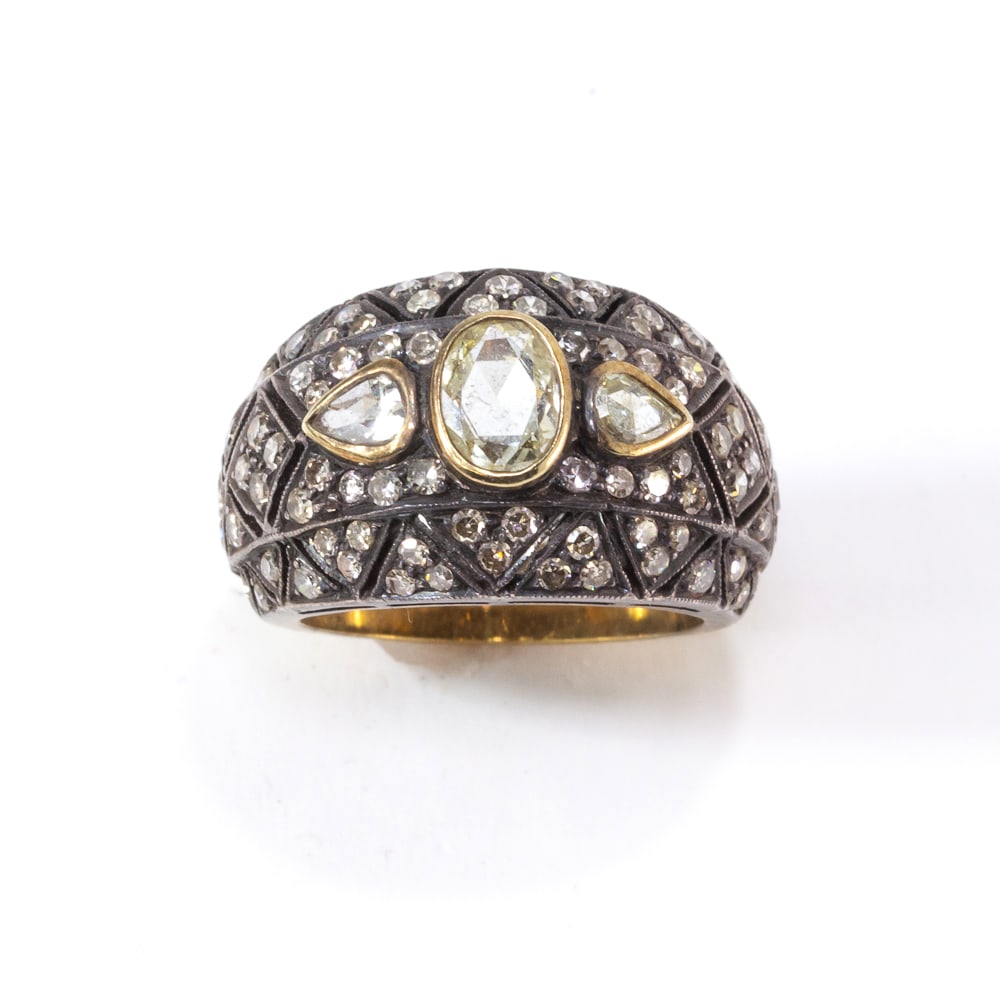 Antique Inspired Diamond, Gold and Silver Ring: Antique style rose and single-cut diamond ring mounted in yellow gold and silver, designed as a slightly domed and graudating band centered by an oval rose-cut diamond with a gold collet, flanked by r
