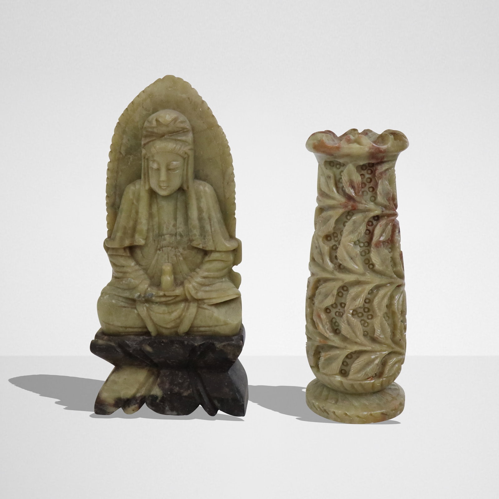 Two Carved Soapstone Articles: Two carved soapstone articles, China, 20th century, comprising a figure of a seated Buddha on an affixed base, and a floral carved vase. [Buddha: 7.5" H x 3.5" W x 2" D]. Condition to each is good; Bu