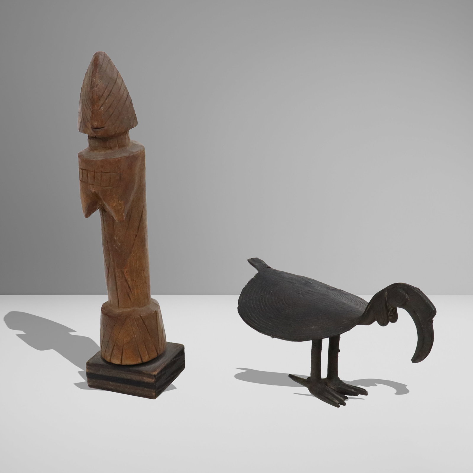 Mossi and Ashanti, Two Objects: Two African objects, comprising a Mossi carved wood fertility figure, Burkina Faso, 20th century, and an Ashanti cast iron crance figure, circa Ghana, 20th century. [Carved wood figure: 9" H x 1.75"
