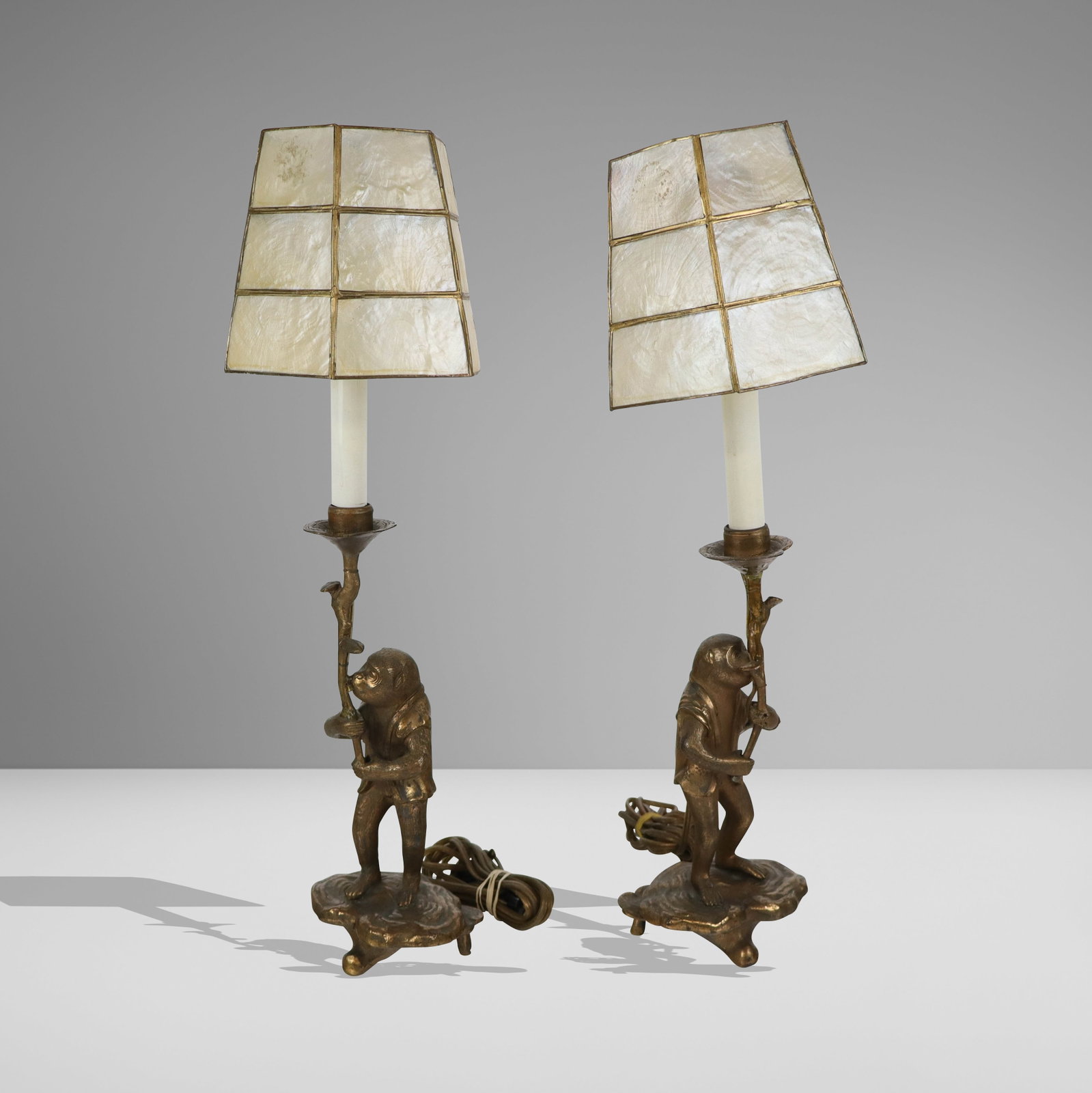 Pair of Gilt Metal Monkey Form Candlestick Lamps: Pair of gilt metal monkey form candlesticks mounted as lamps, 20th century, with shades. [11" H to Bobeche, 5.5" W x 3.5" D]. Overall condition is good/fair, with losses to gilding and residue, not te