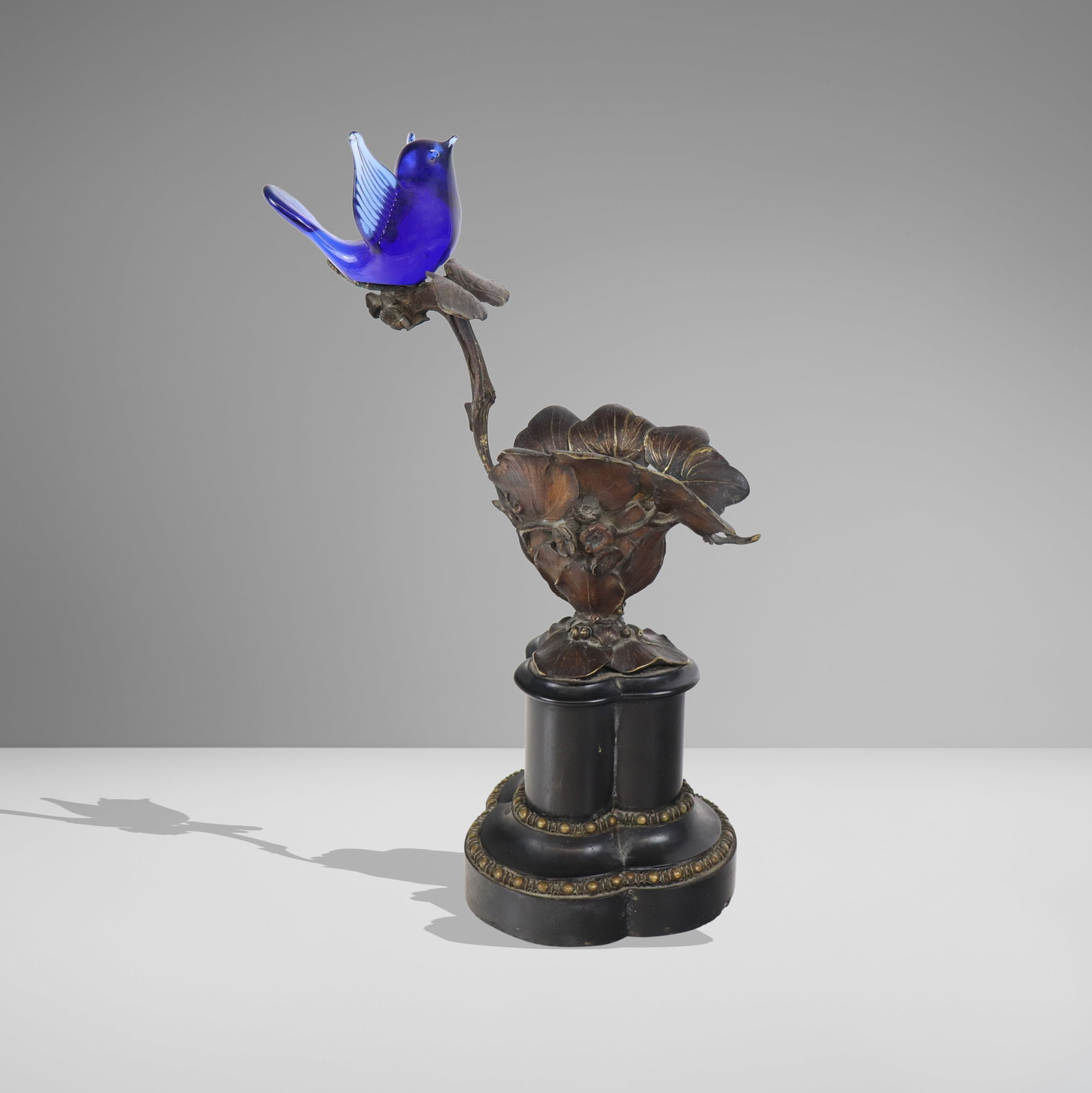 Art Nouveau Inspired Bronze & Glass Sculpture: Art nouveau inspired bronze flots form sculpture with glass bird accent, second quarter of the 20th century, designed as leaf form cup accented with buttercups a rising tendril supporting a blue glass