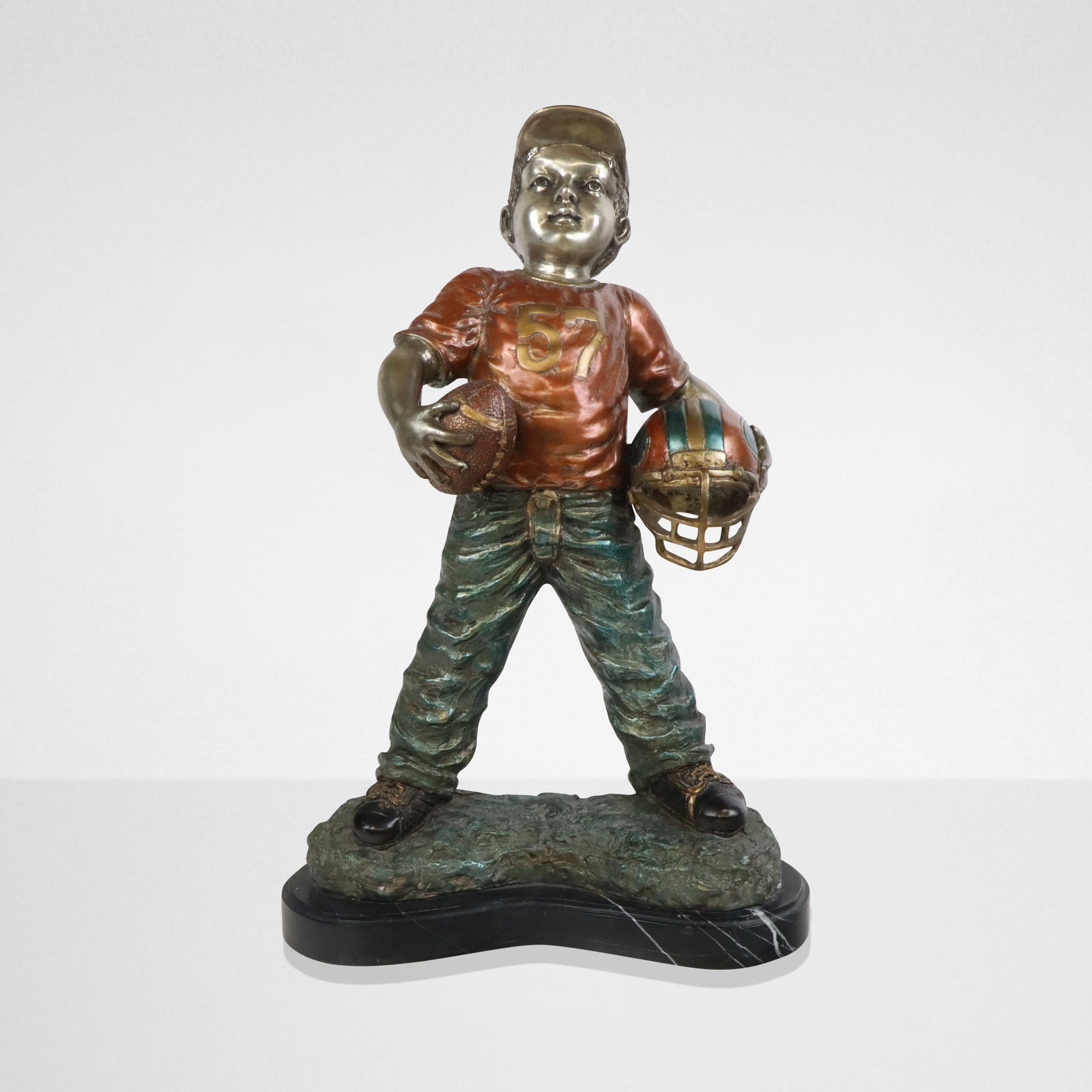 Bronze on Marble Sculpture of a Football Player: Painted bronze of a young football player, 21st century, with painted finish, on a marble base, signed illegibly to lower reverse. [25" H x 17" W x 7" D]. Condition is good.