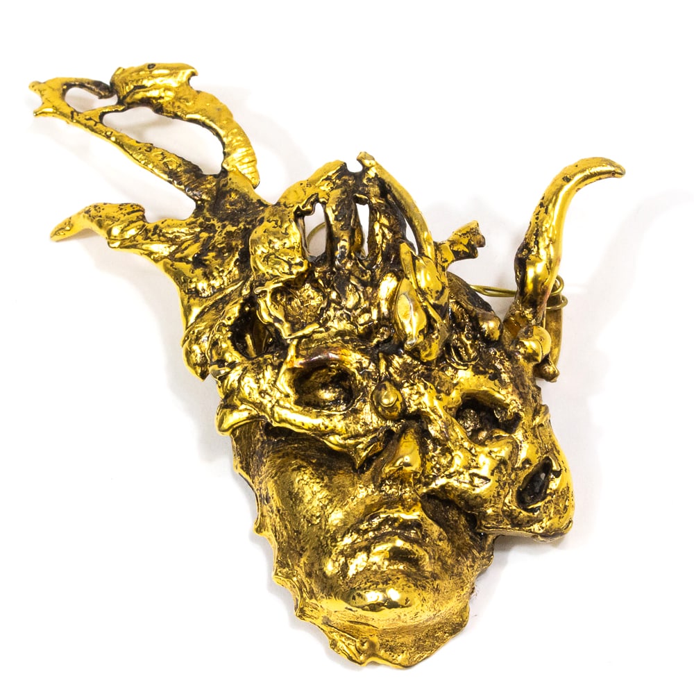 Att. Ailene Fields Gilded Masked Jester Pendant: Attributed to Ailene Fields gilded metal masked jester pendant expressedly modeled in the Brutalist style, unmarked. [3.25" H x 3" W]. Overall condition is good/fair, with some unfinished or uneven pa