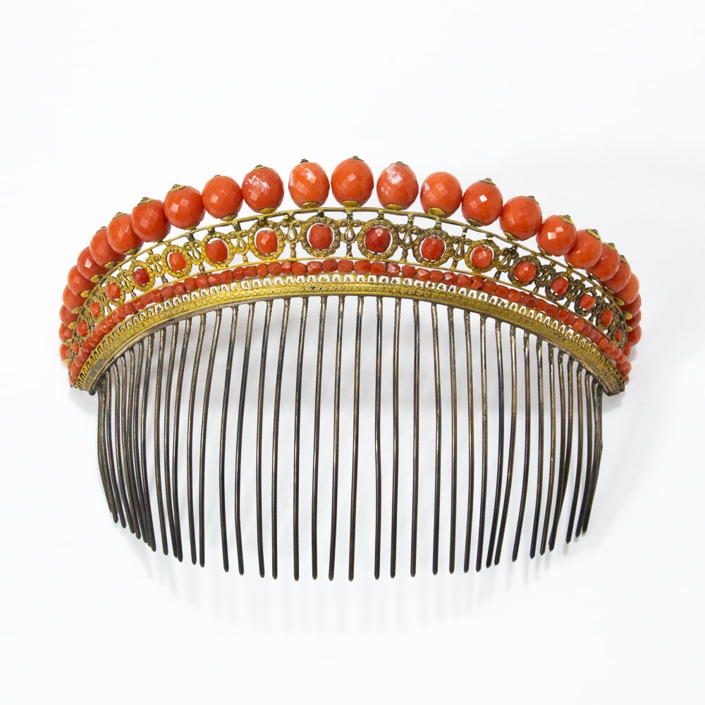French Empire Coral & Gilt Metal Hair Comb: French Empire coral and gilt metal hair comb, late 18th century, the arched pierced band surmounted by faceted coral beads, above a conforming row of smaller beads enclosed in gilt metal foliate wreat