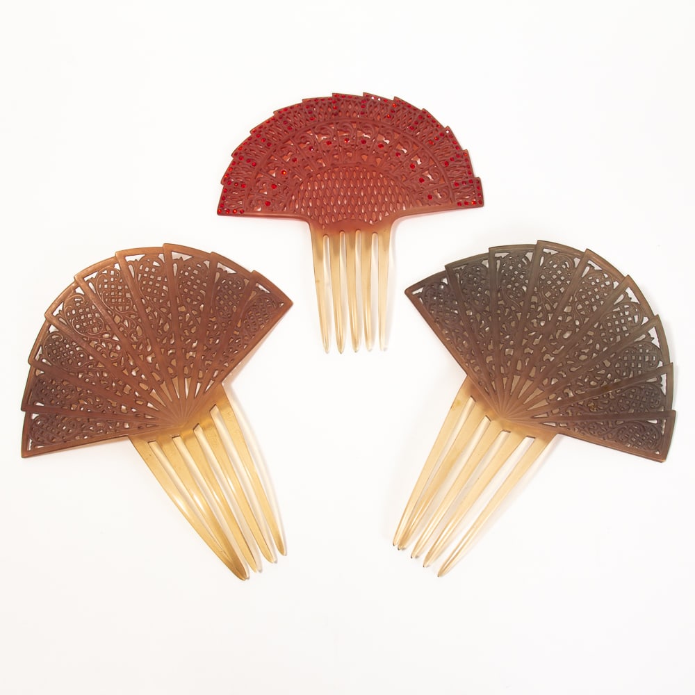 Three Pierced Fan Form Celluloid Hair Combs: Three pierced fan form celluloid hair combs, early-mid 20th century, comprising a red comb enhanced with faux jewels, together with a companion pair in tones of blue-gray and camel. [Larger (pair): 7.
