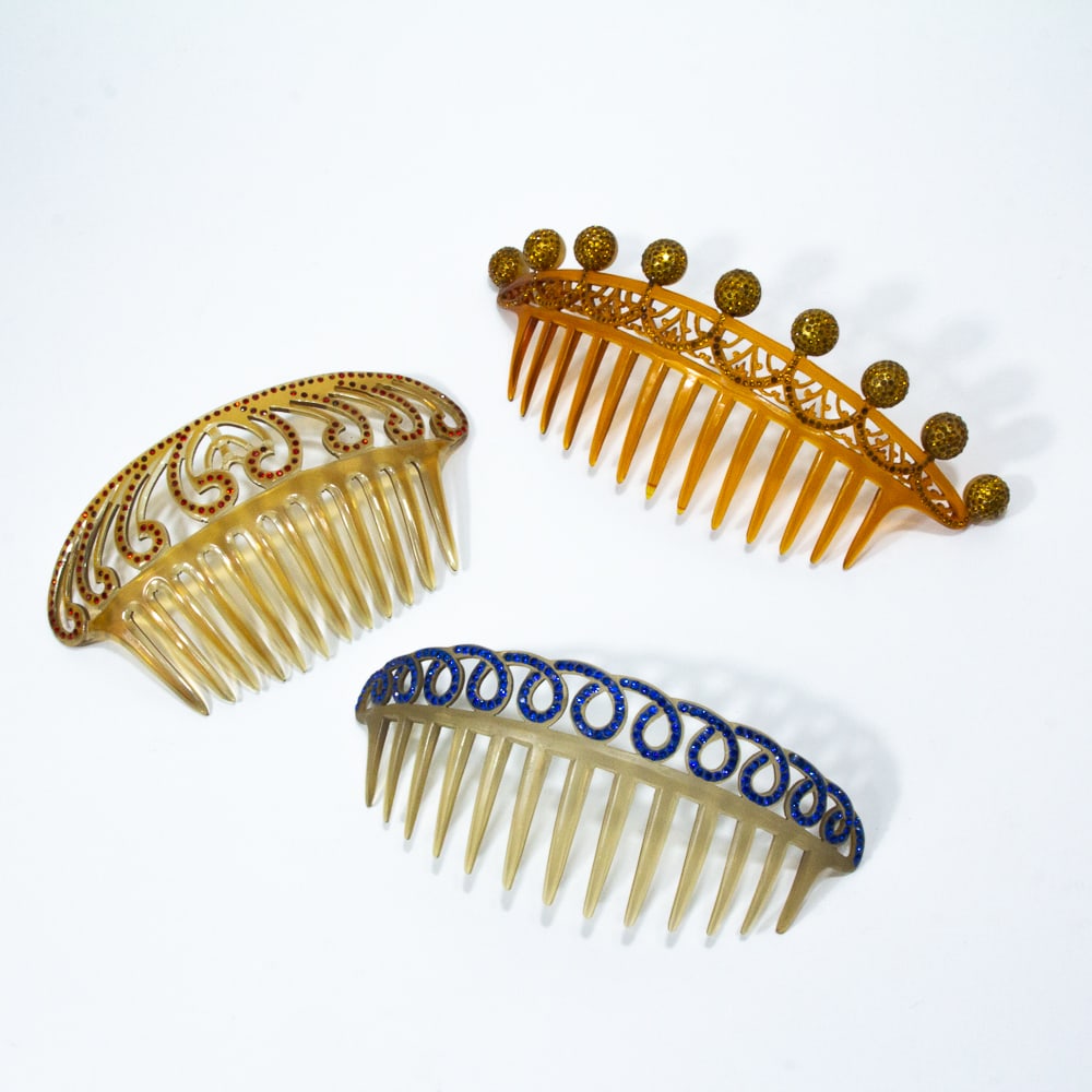 3 Vintage Celluloid Faux Gem Decorative Hair Combs: Three vintage celluloid faux gem set decorative hair combs, probably first half 20th century, one in amber/orange tones with spheres, one with blue loops, the last with red stylized feathers. [Largest