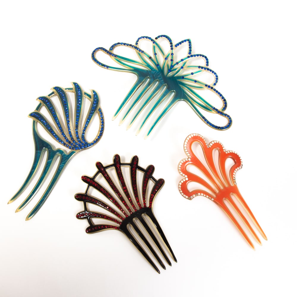 Collection of 4 Vintage Celluloid Faux Gem Combs: Collection of four vintage celluloid faux gem combs, early-mid 20th century, comprising two blue examples, a black and red example, and a faux coral comb. [Largest: 6" H x 8" W]. Overall in good condi