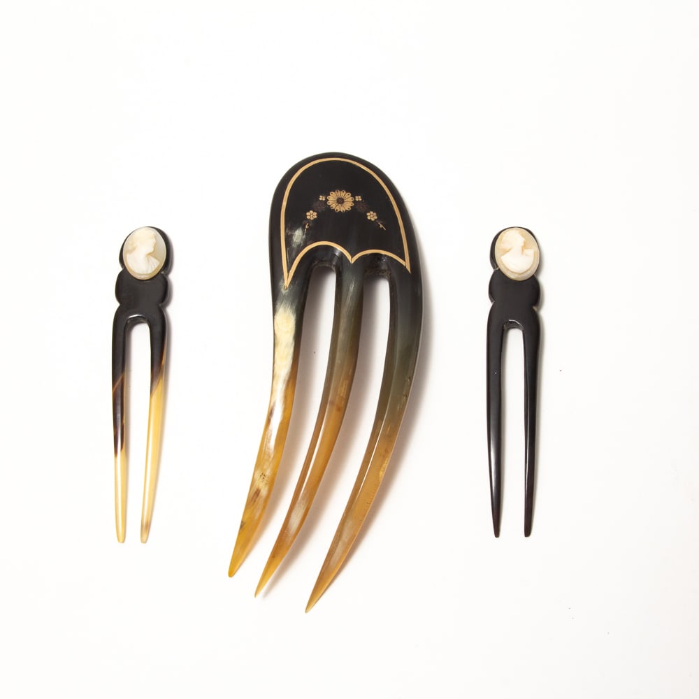 Three Art Nouveau Carved Horn Hair Combs: Three Art Nouveau carved horn hair combs, late 19th-early 20th century, including a large three tine comb with gold pique floral decorations and a pair of two tine cameo pins. [Larger: 6" L x 2" W; Sm