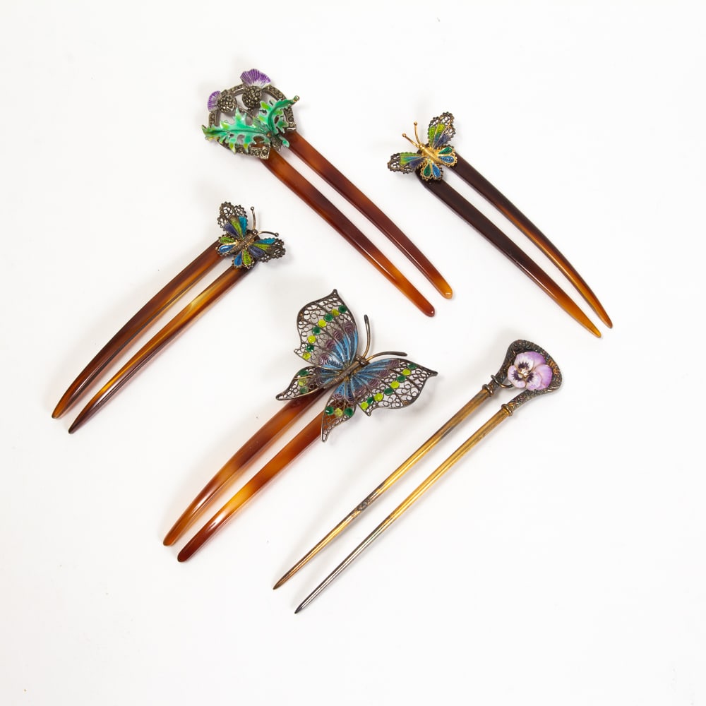 Group of 5 Enamel Decorated Hairpins: Group of enamel decorated hairpins, 20th century, all having two tines, including three butterfly combs, one horseshoe form with flowers and foliage, and a metal comb with a relief crest and central p