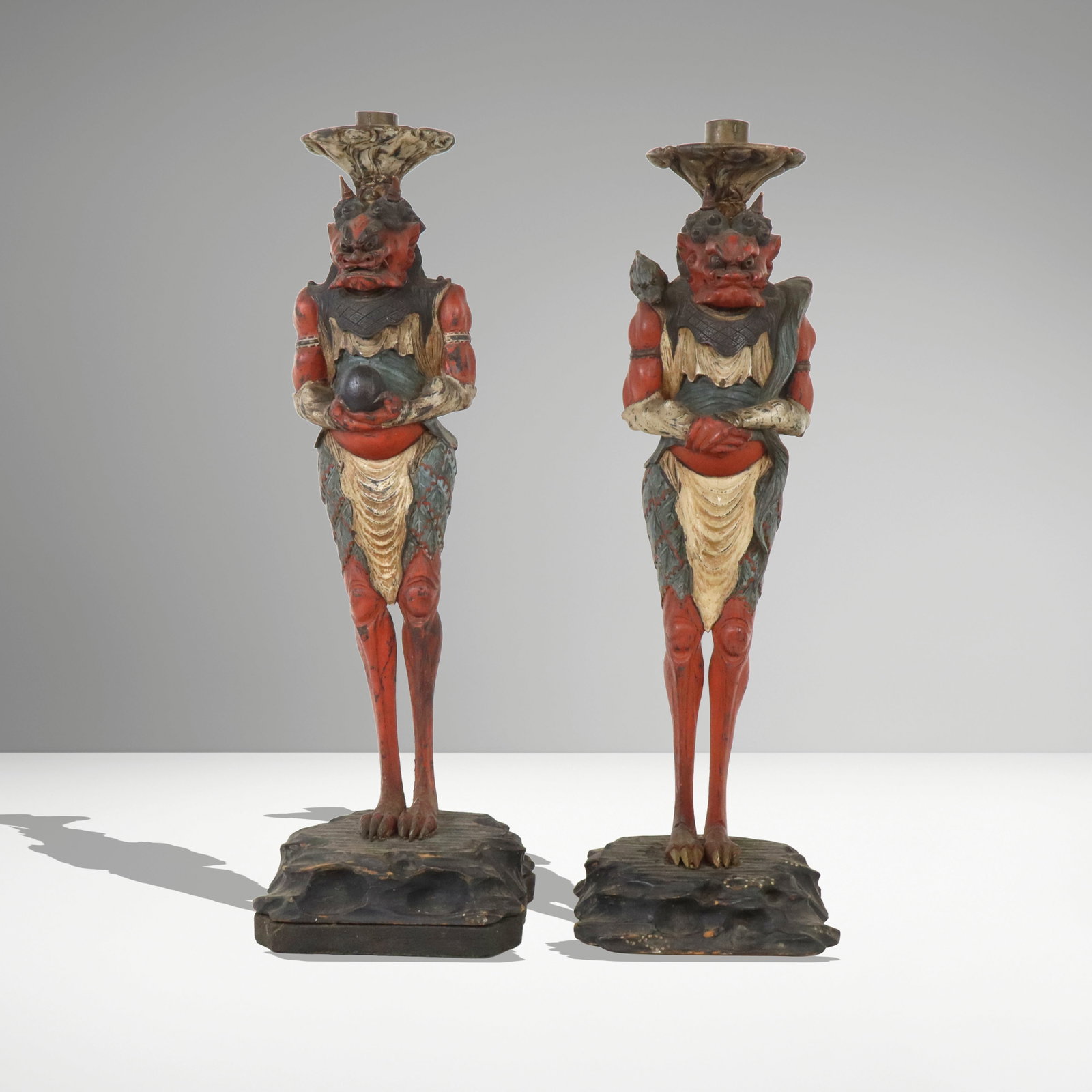 Pair of Carved Wood Japanese Oni Form Candlesticks: Complimentary pair of carved and painted wood candlesticks, Japan 19th/early 20th century, in the form of two Oni, one on an affixed base. [21.5" H x 7" W x 6" D]. Condition is good with some minor