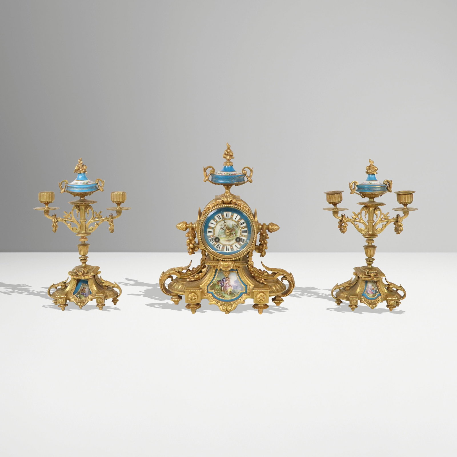 Japy Freres Louis XV Gilt Bronze Clock Garniture,3: Louis XV gilt bronze and porcelain decorated three piece clock garniture, French, second half of the 19th century, comprising a clock and a pair of two light candelabra en suite, each ornately