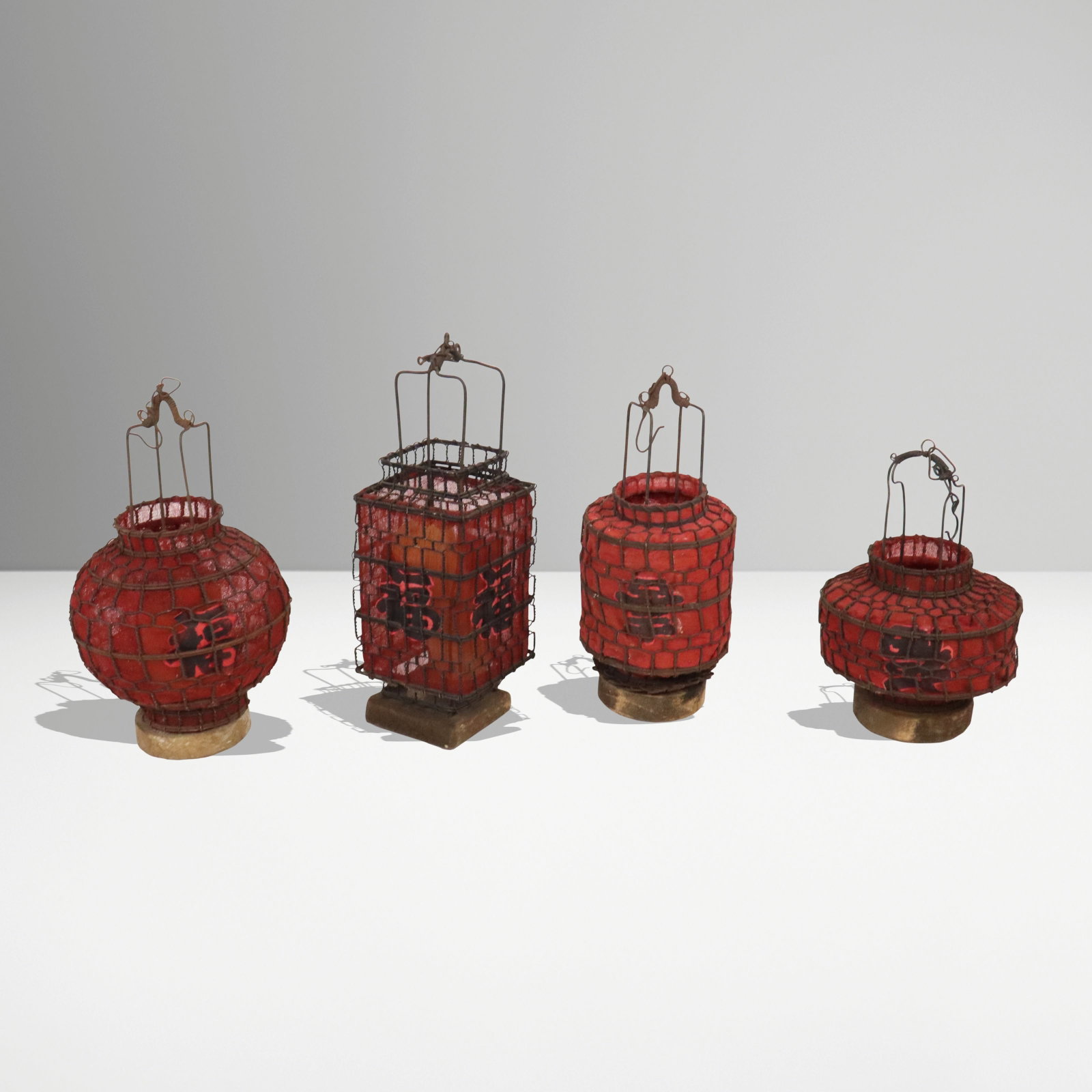 Four Chinese Hanging Lanterns: Four Chinese hanging lanterns, 20th century, with chicken wire and red fabric construction, each with characters to sides. [Tallest: 10.5" H x 3.5" square]. Condition is good with age-commensurate rus