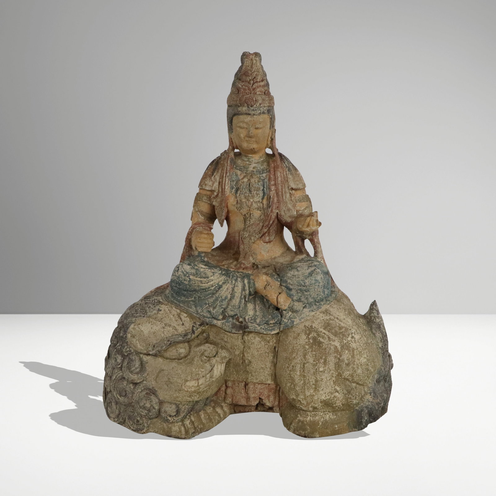 Chinese Carved Wood Figure of a Seated Buddha: Chinese carved and painted wood figure of Buddha, 19th century, with the figure seated atop a foo dog. [19.5" H x 18" W x 13" D]. Condition is good with cracks to wood and losses to paint.