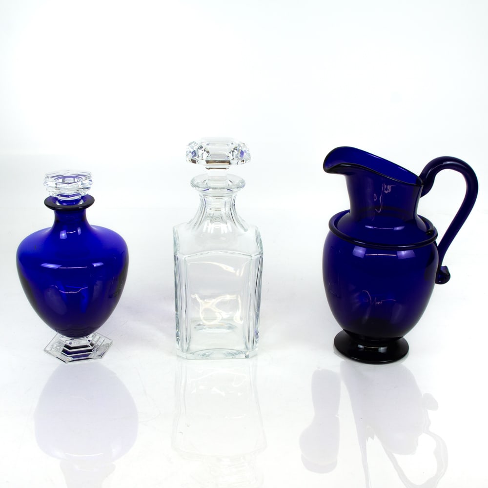 Baccarat & MMA Colorless & Blue Glass Articles, 3: Collection of assorted colorless and cobalt blue glass articles, comprising a Baccarat blue and clear stoppered decanter [8.25" H x 5" Diameter], a Baccarat colorless glass square decanter [9.5" H x 3
