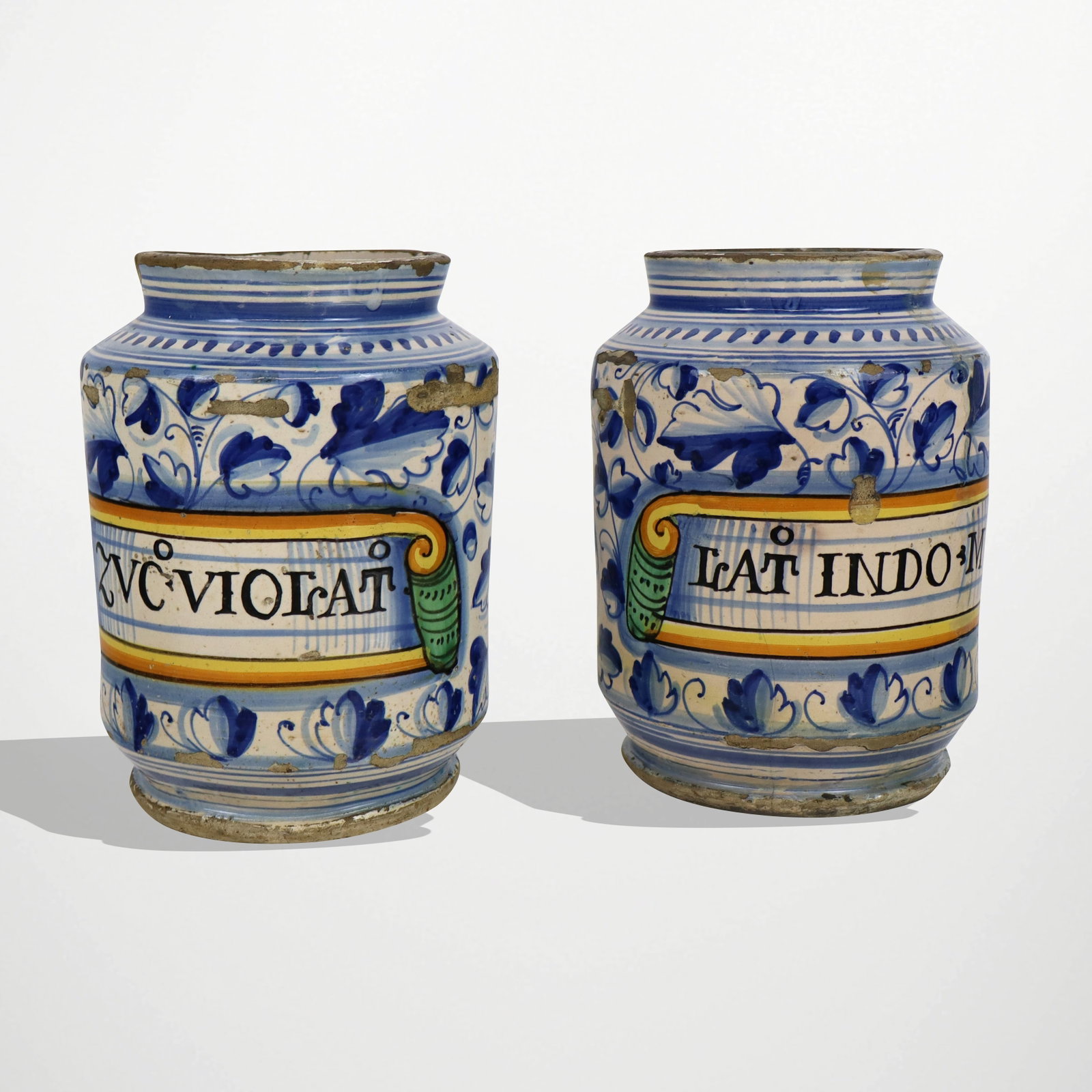 Two Italian Maiolica Albarelli: Pair of ceramic decorated maiolica albarelli, Italian, possibly Montelupo, probably late 16th century, each painted with leafy vines, one labeled ZVC?.VIOLAT, the other labeled LAT? INDO M. [7.25" H x