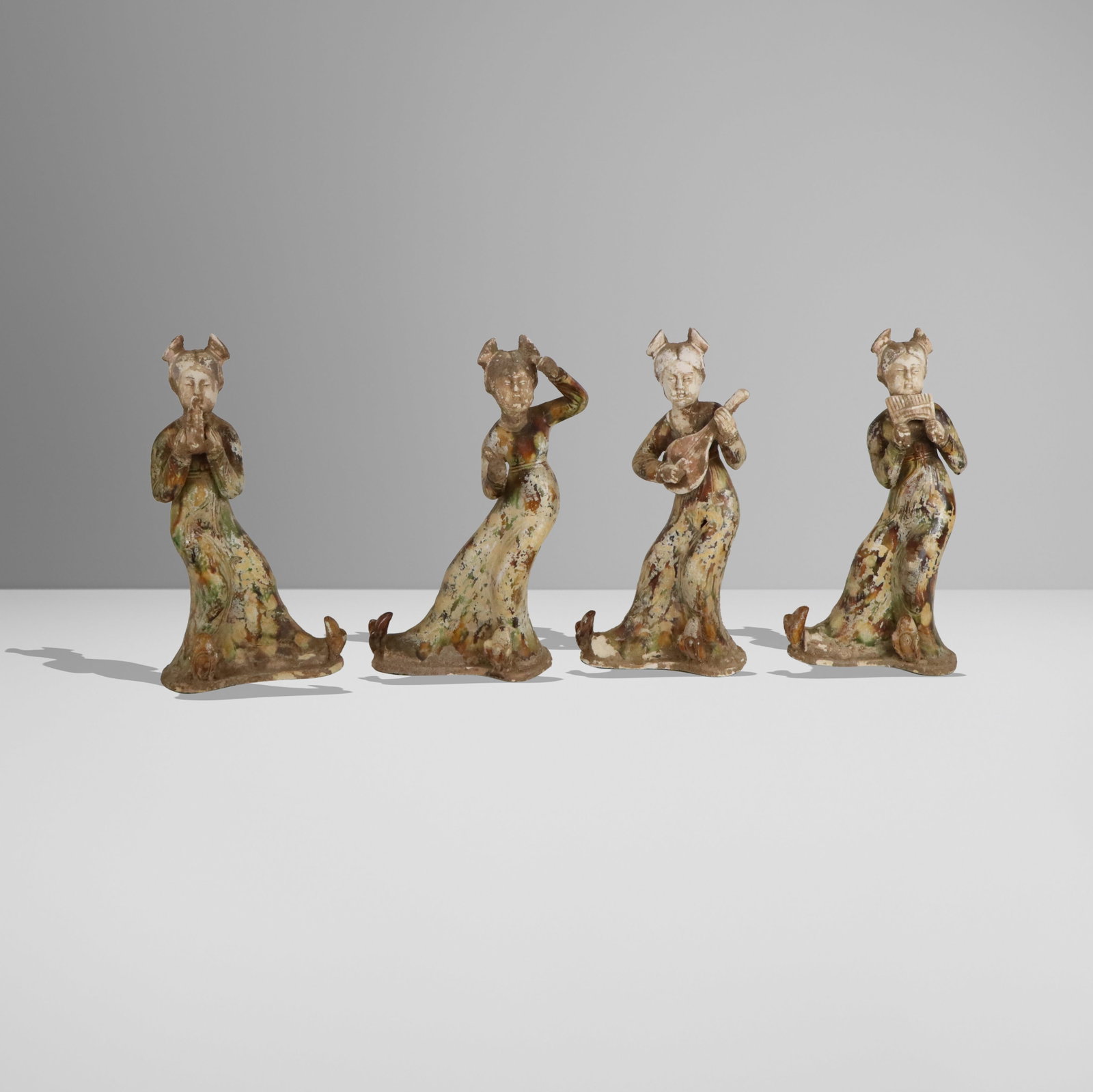Four Chinese Figures after the Tang: Four Chinese figures after the Tang, 20th century, each with different instruments and sancai decoration. [13.5" H x 7" W x 5" D]. Condition throughout is good with simulated and regular wear and loss