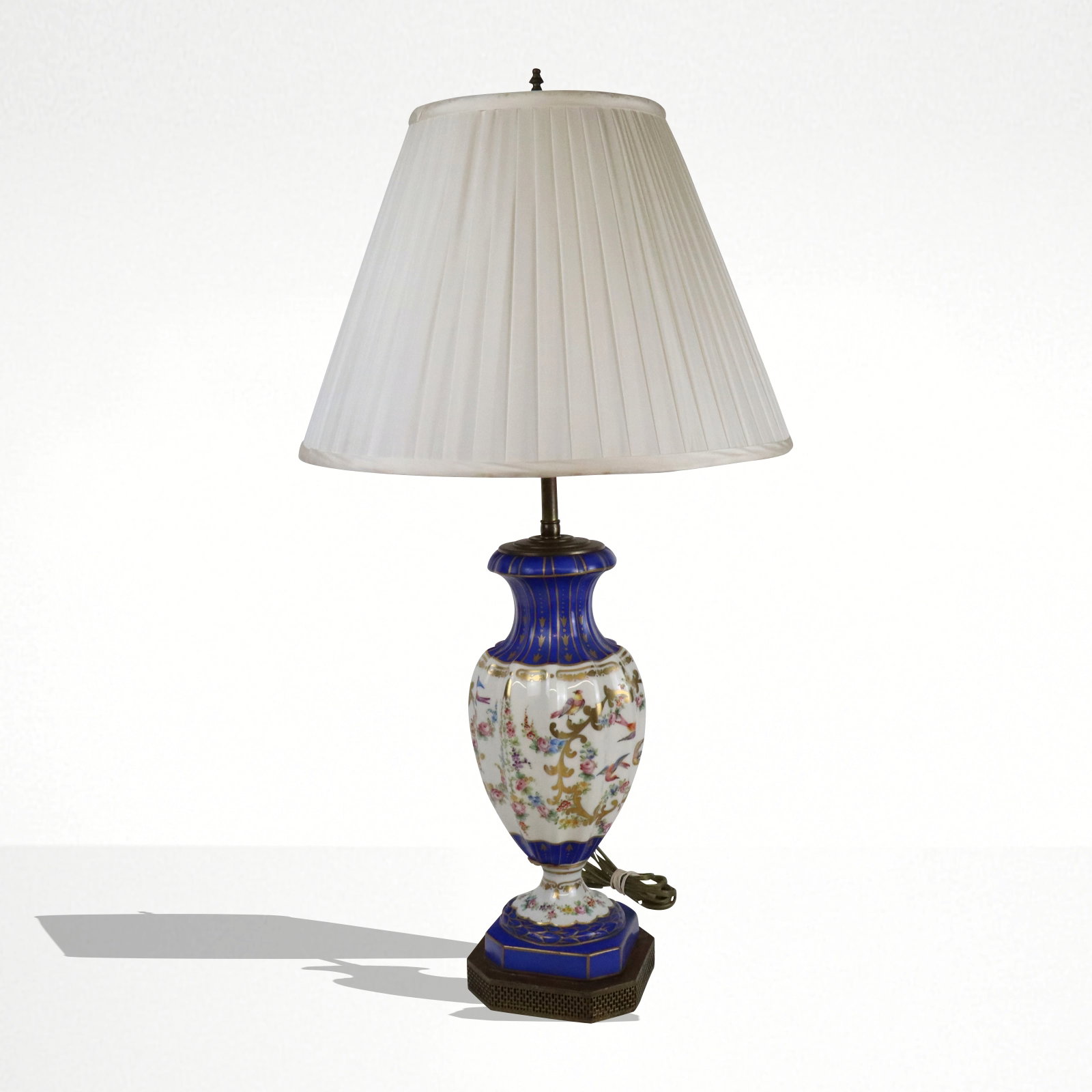 French Porcelain Vase as a Lamp: French porcelain vase, 19th century, with hand applied bird, floral, and gilt decoration, mounted on pierced brass with a white shade. [Less shade: 26" H x 5.5" Diameter]. Condition is good.