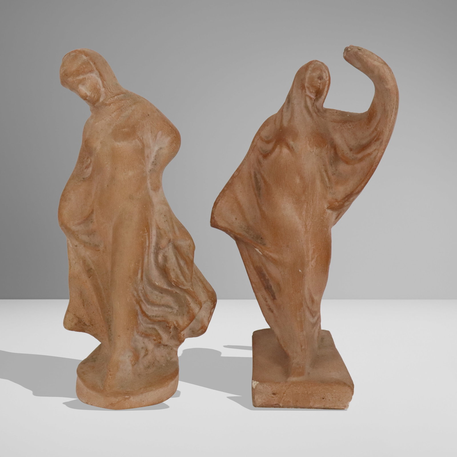 Two Terra Cotta Figures: Two terra cotta figures, early 20th century, one with Robert F. Simmons attribution to base. [Taller: 9" H x 4" W x 3.5" D]. Condition to each is good, shorter with losses to corners at base.