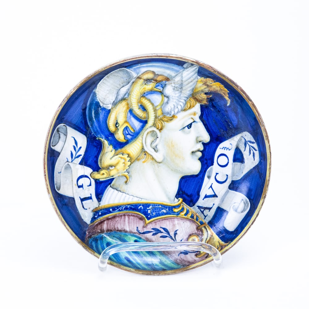 Antique Maiolica Shallow Bowl: Antique maiolica shallow bowl, Italian, possibly Urbino, depicting a bust of Glasco as an illustrious ancient hero with fantastic helmet. [8.5" Diameter]. Overall condition is fair, with repair and da