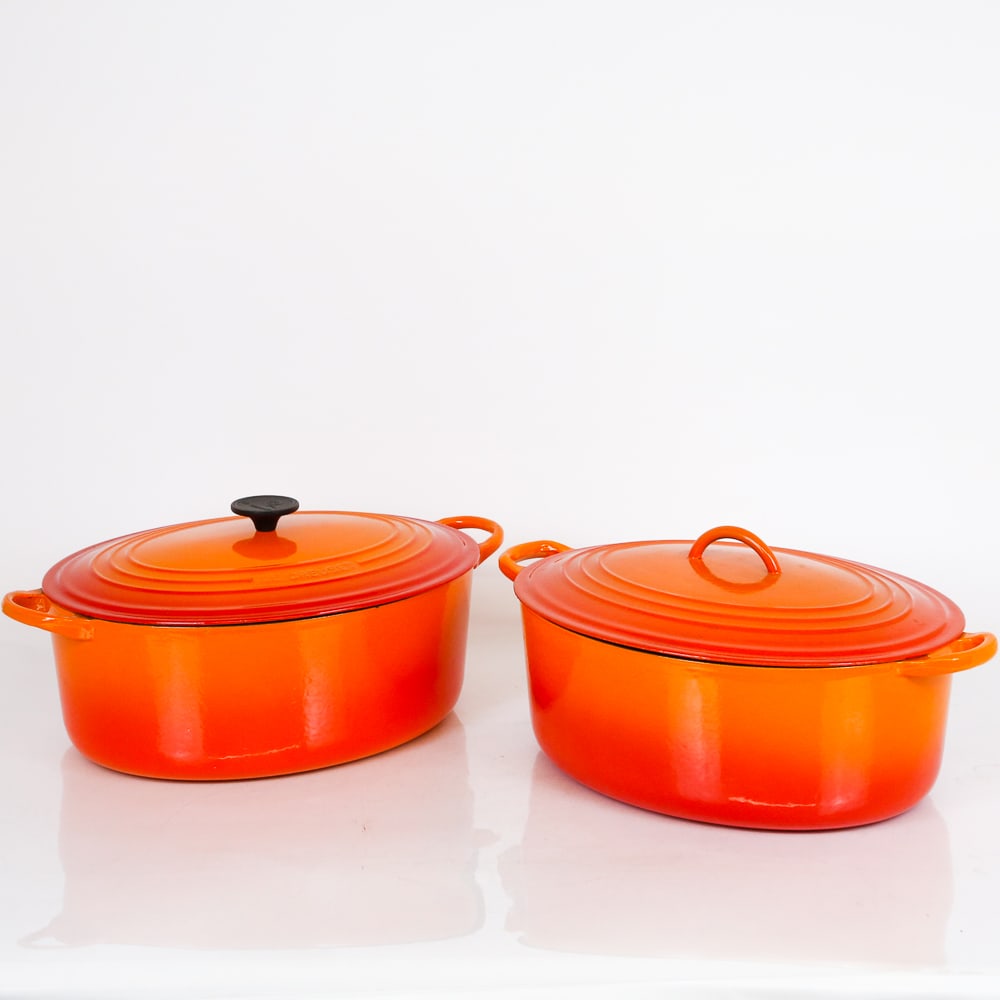 Le Creuset Two of Orange Dutch Ovens: Le Creuset two orange enamel Dutch ovens, mark to base and top. [7.5" H x 17" L x 11.25" W]. Overall condition is good, one in very good condition, the other with normal wear, small chip, and slight