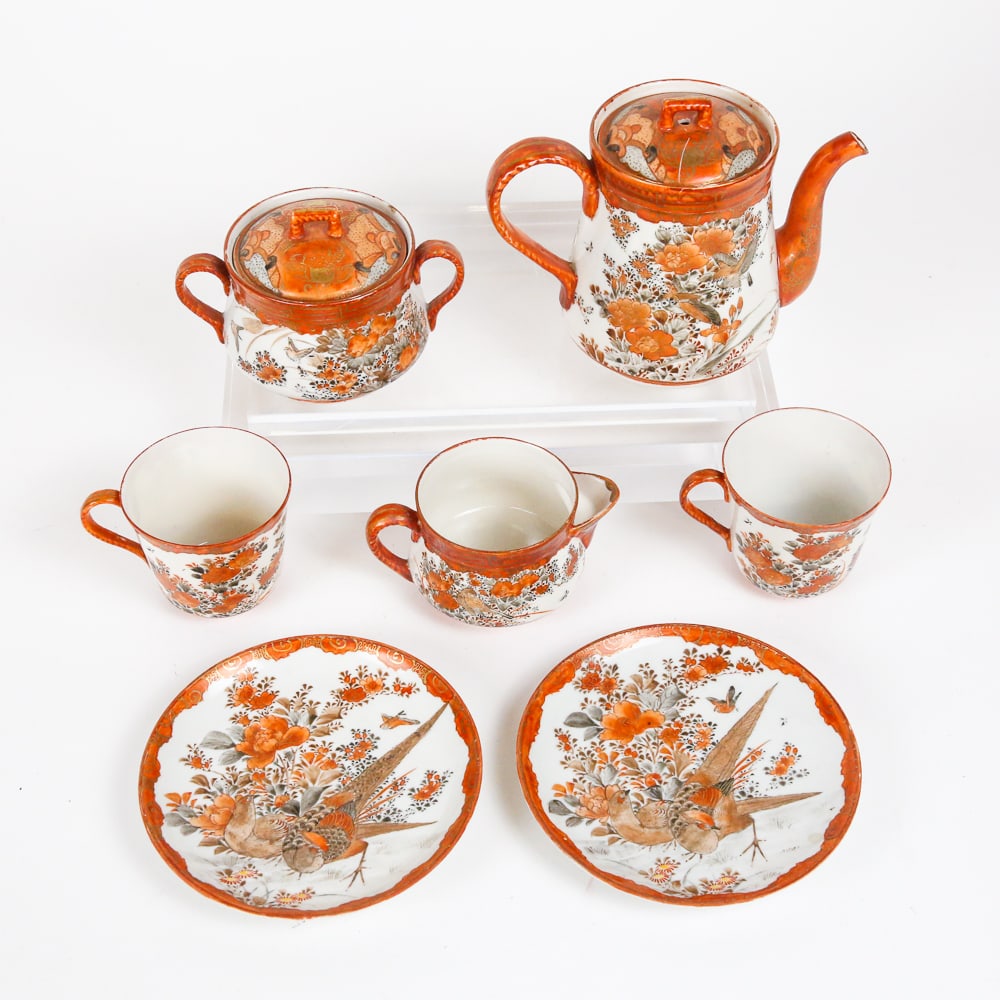 Japanese Export Porcelain Tea Set: Japanese export porcelain tea set with elaborate hand-painted details on red ground, marked to bases. [Teapot: 5.25" H x 7" W x 4" D]. Condition is good with minor surface wear.