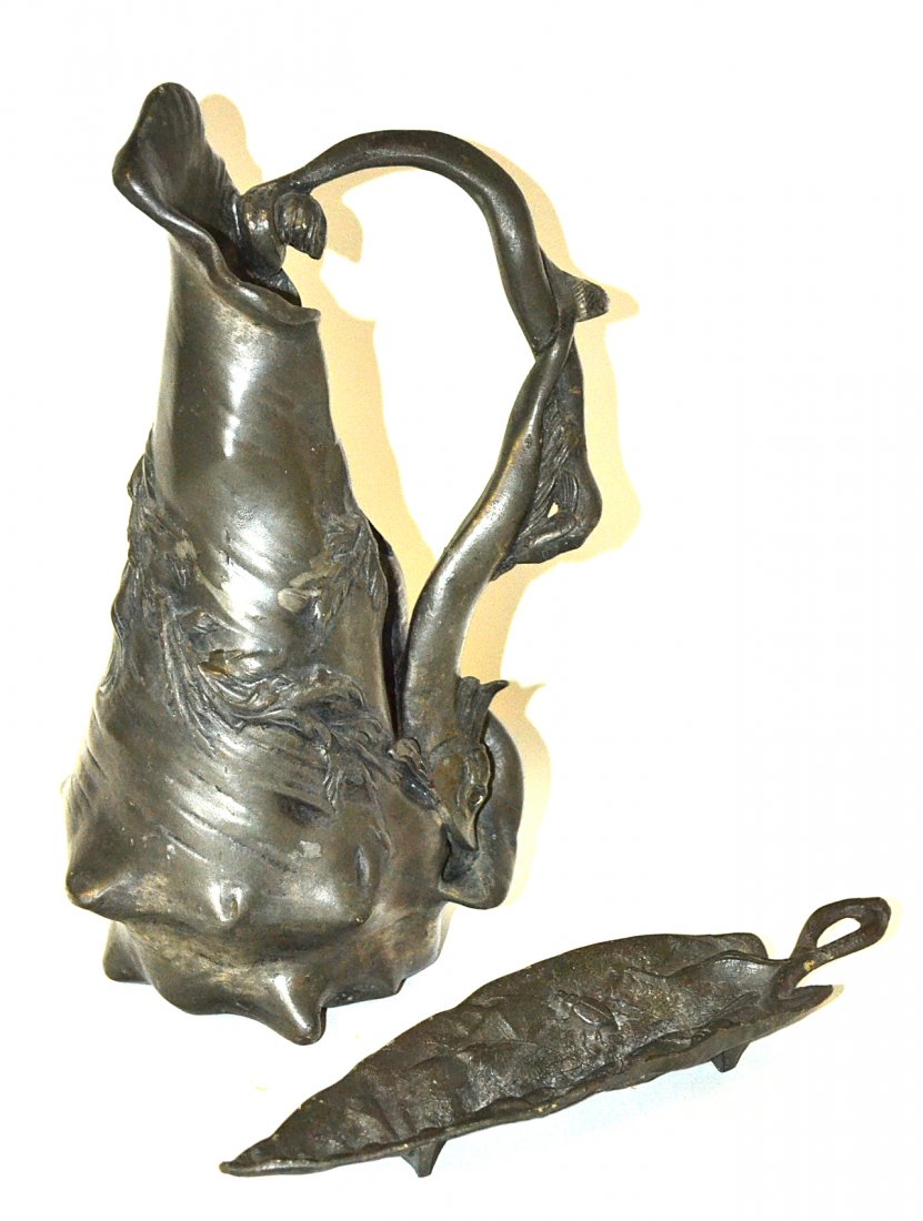 Etain Geranti Art Nouveau Pitcher & Other: Pewter pitcher with a shell form bottom seawood body and dolphin form handle. Marked on bottom "Etain Garanti/Pur/Paris". [6 1/4" x 4 3/4" x 10 1/8" H]. Accompanied by an Art Nouveau naturalistic leaf