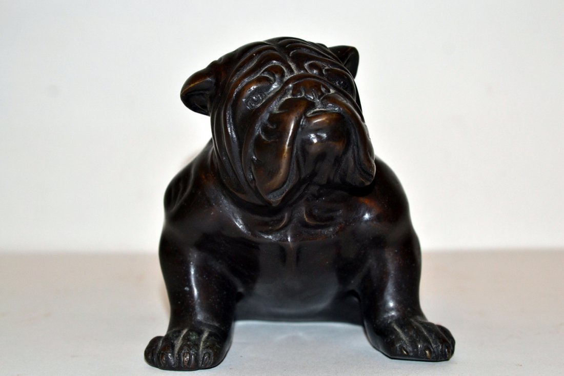 Bronze Bulldog Sculpture: Full length depiction of a bulldog seated on hind legs. Unsigned. Bears a dark brown patina. [5 1/8" w x 7 5/8" d x 5 1/8" h].