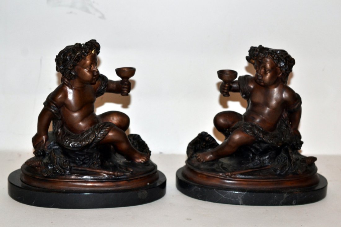 Pair of Rossi Cherub Bronzes: Pair of seated cherub bronzes on marble bases. Each holding wine glasses. [8" l x 7 1/2" h (sculpture only) x 8 1/2" h (overall)].