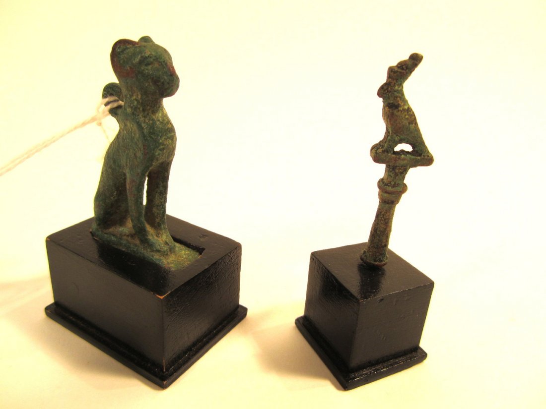 Two Ancient Egyptian Bronze Animals: Comprises: 1). Cat resting on hind quarters [1/2" w x 1 1/4" d x 2 1/8" h]. Bears a small ring on back of neck. 2). Diminutive bird perched atop small column [1/4" w x 9/16" d x 2" h]. Both bear uneve