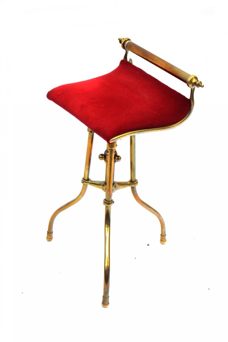 Brass Piano Stool: Brass piano stool with red upholstery. The frame is bent, and will require restoration.[25" h x 14 3/4" w x 10" d].