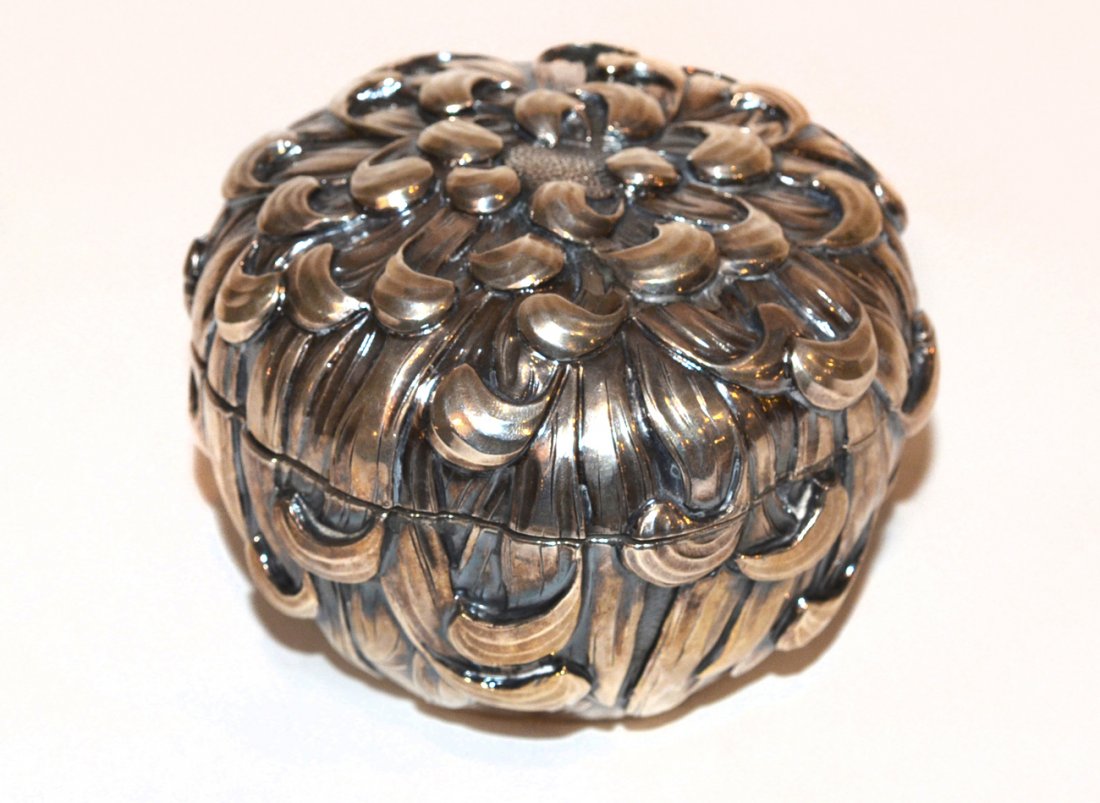 Japanese Sterling Powder Box: The circular box modeled as a chrysanthemum and having silver mounted puff. There are no dents, cracks, or repairs. The box is complete and intact. [3 1/2" h x 4 1/2" dia]. 10 ozt.