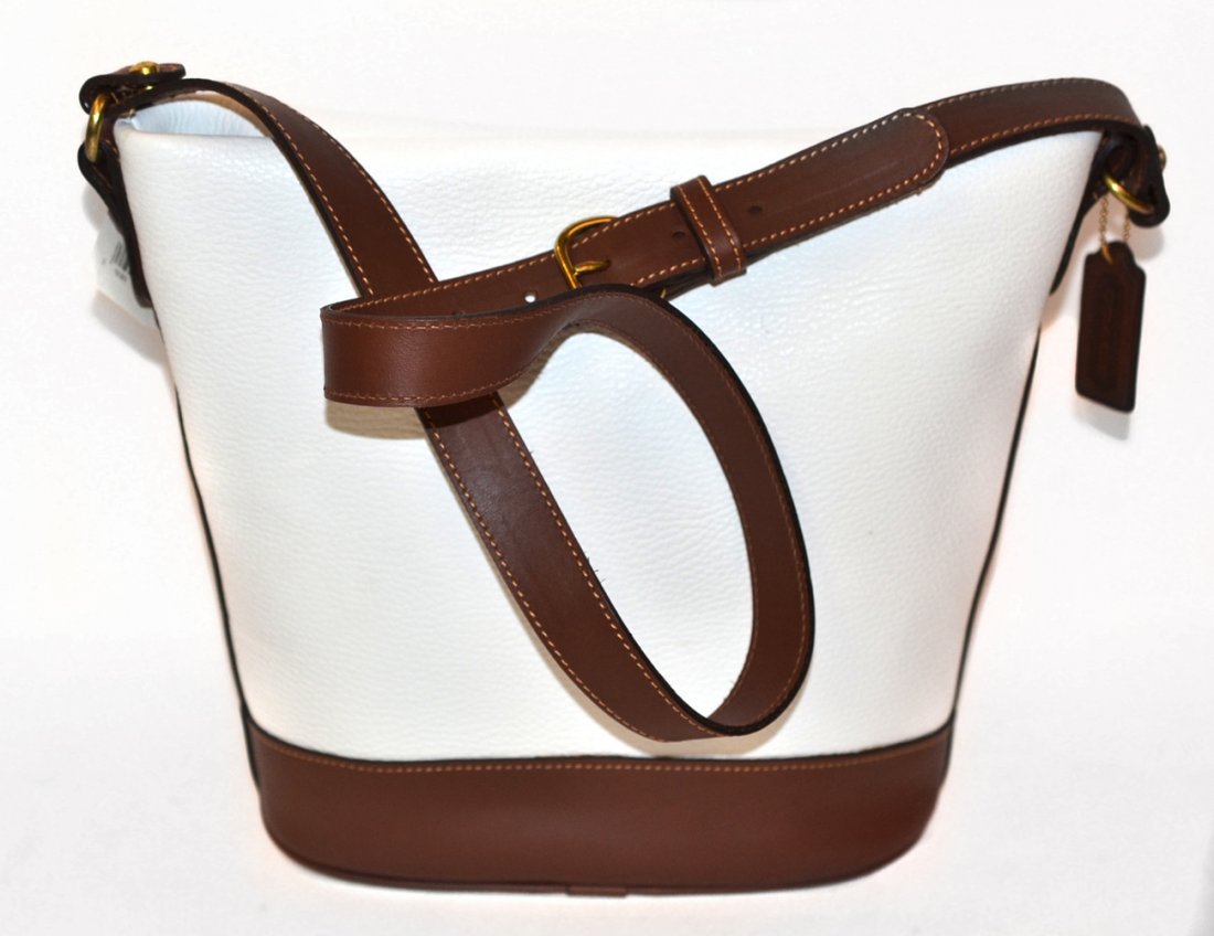 Coach "Sheffield" Bag: Pebbled white leather with brown accents, one interior compartment. In very good condition. [9 1/2" w x 5" d x 10 1/2" h (bag only)].