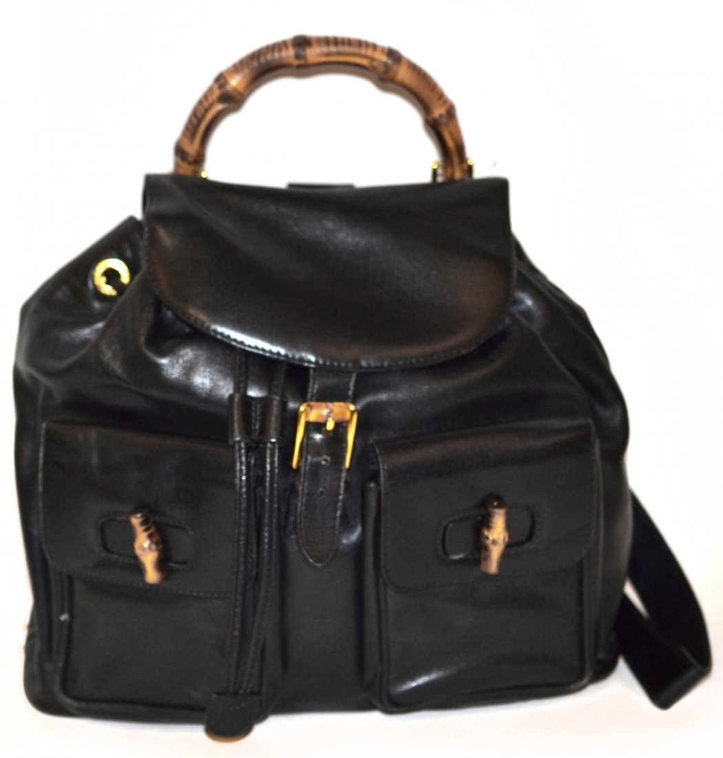 Gucci Black Leather Backpack: Bamboo handle and toggles, two exterior compartments with flap closures. One interior compartment with zipper closure. Some light wear on base and edges, and loose stitching. [12" w x 4" d x 12" h (ba