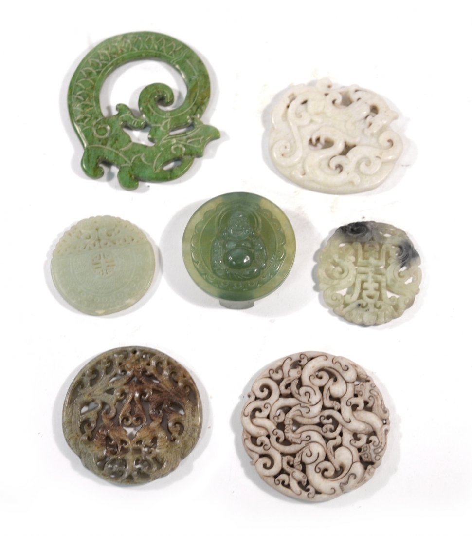 Seven Chinese Hardstone Medallions: Circular and oval medallions with variously carved, reticulated, open-work and relief surfaces. Subjects/ornament includes: dragons, Buddha, birds, and a calligraphic character.