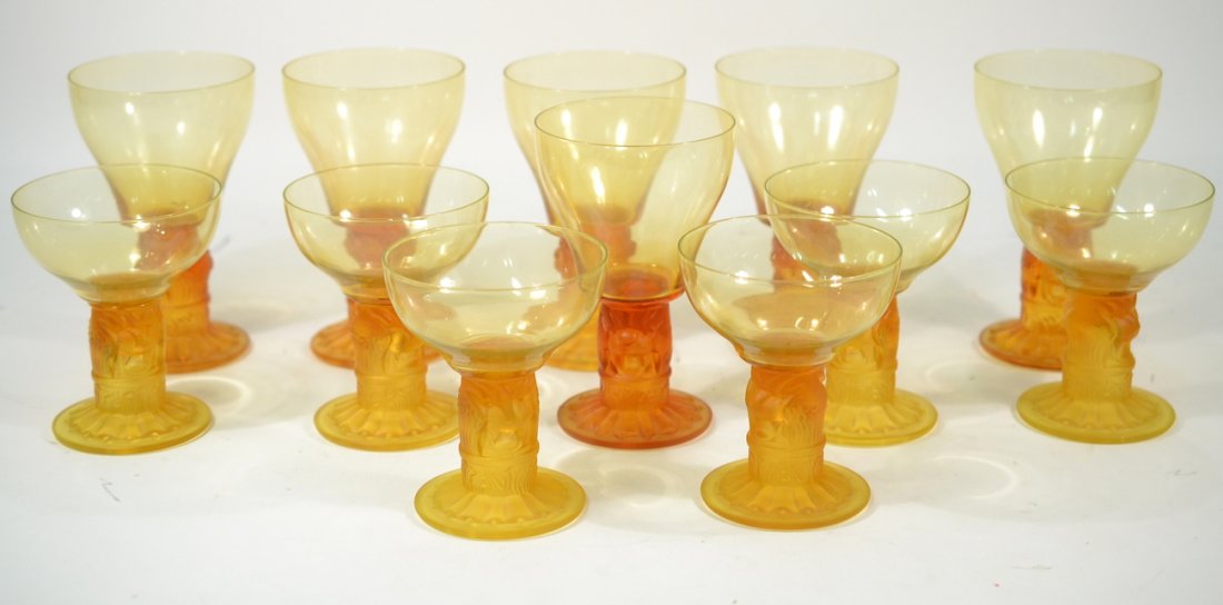 After Lalique, 12 Art Deco Stems: Set of 12 mould-formed and frosted amber glass stems comprising six water glasses and six wine glasses.[Water glasses: 3 5/8" x 7 5/8"; Wine glasses: 3 3/4" x 4 1/2"]. All in good condition.