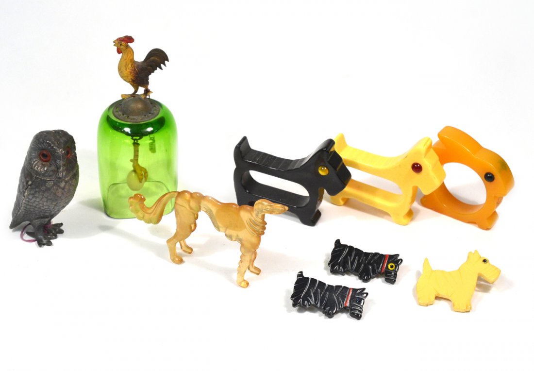Nine "Animal" Decorations: Comprises rooster dinner bell with egg form clapper, 3 bakelite terrier pins, 3 bakelite napkin rings, plastic model of an afghan hound and a silvered-metal owl. Good condition