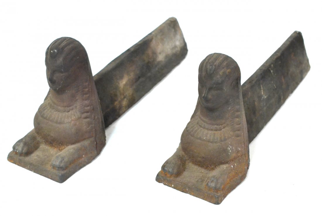 Pair Antique Egyptian Revival Andirons: Cast iron sphinx-form andirons (no foundry mark). [4 3/4" W x 17 1/2" D x 7" H]. Areas of light oxidation.