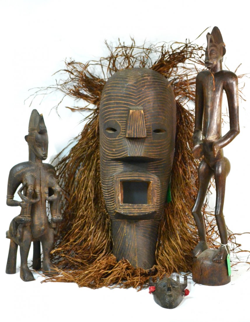 Four African Carved Wood Articles: Comprises: 1.) Large carved and incised mask with dry grass surround. [Carved wood only: 12 1/4" W x 11 1/2" D x 34" H]. 2.) Sculpture depicting a standing figure with distended belly and incised scar