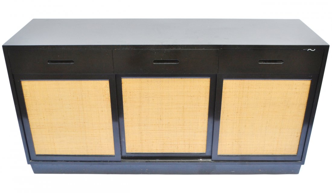 Dunbar Mid-Century Modern Sideboard: Black painted sideboard with three drawers fitted for flatware above three sliding woven jute panels concealing three drawers at either end and shelves below. [61 1/2" x 18" x 32 1/8" H]. Scratches an