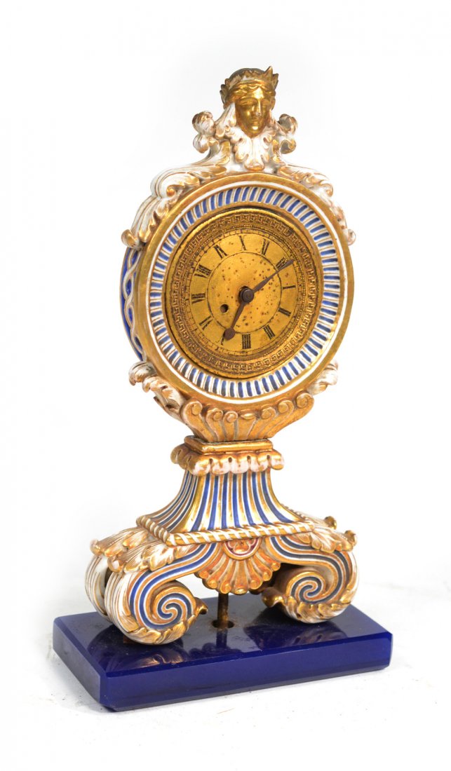 Antique Continental Porcelain Clock: Possibly French or Russian. Blue, white and gilt porcelain clock with brass face and glass base. Wear commensurate with age. Works not tested. [9 1/4" H x 4 7/8" W x 2 3/8" D].