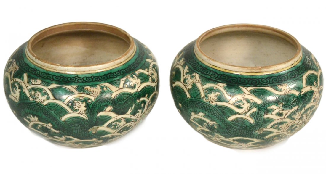 Pair of Antique Asian Dragon Bowls: Green and white bowls, each depicting two dragons among turbulent waves and a jutting rock. Both bear an incised leaf mark on the bottom. [5 1/8" Dia. x 3 1/8" H] Light soiling.