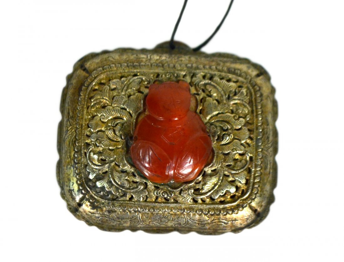 Chinese Carnelian-Silvered Metal Pendant: Ornately chased rectangular pendant mounted with antique carved carnelian figure of a deity. [2 3/4" W x 2 3/8" H x 1/2" D]. Good condition.