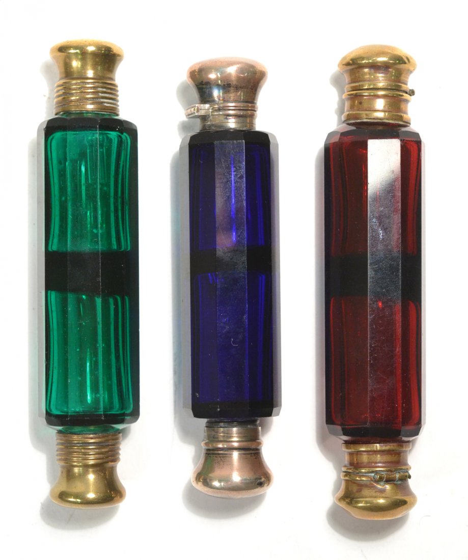 Three Victorian Glass Perfume/Salts: Cut colored glass. Circa 1890. Double-end mounted facet-cut ten-sided cylindrical perfume salts. Comprises: 1.) Ruby glass with brass fittings (one hinge broken). [5 1/4" L]. 2.) Cobalt glass with sil