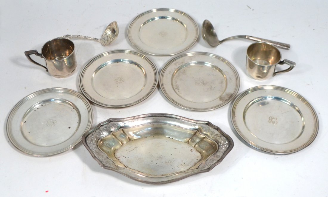 Group of Assorted Sterling Articles: 10 table articles includes two children's cups, set of five bread and butter plates, two sauce ladles, and a bread tray. 19.87 ozt. Some dents--fair to good condition.