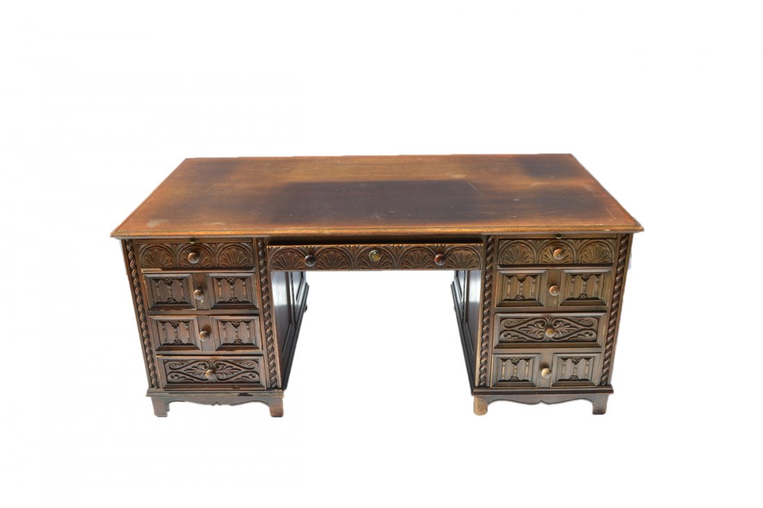 Tudor-Style Executive Desk: Oak carved desk having all drawers. [69 1/2" W x 37" D x 30 1/2" H]. Scratches and wear.