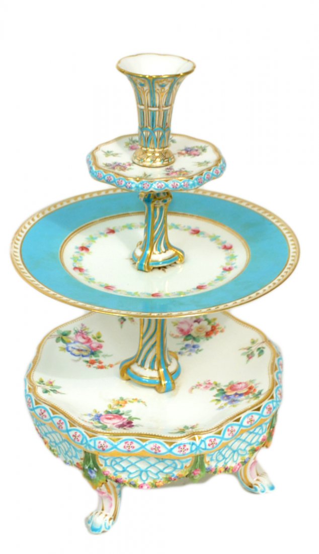 Three-Tier Porcelain Cake Stand: Assembled stand with floral decoration. [14" H]. Second tier replaced, hairline crack, and wear to gilding.